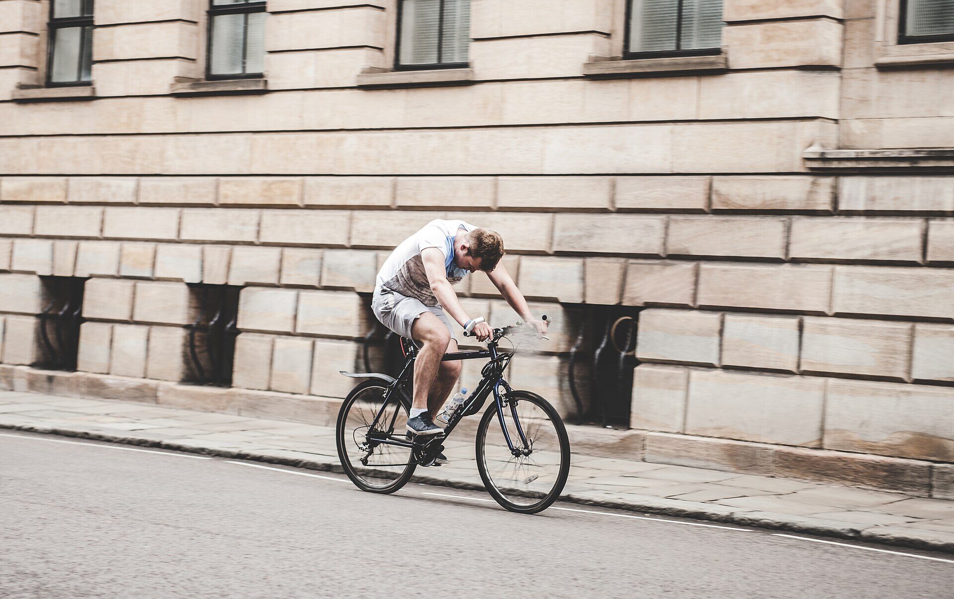Ciclista urbano pedaleando junto a un edificio de cantera