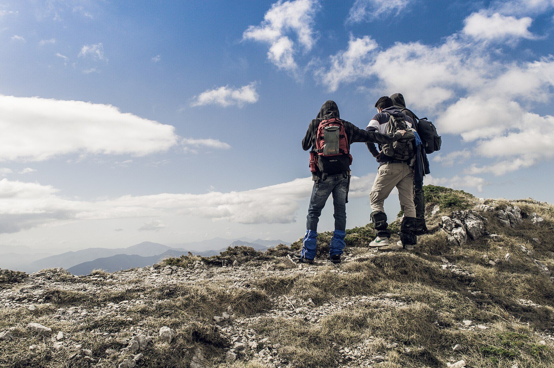 Dos excursionistas de pie sobre una roca con vista a las montañas