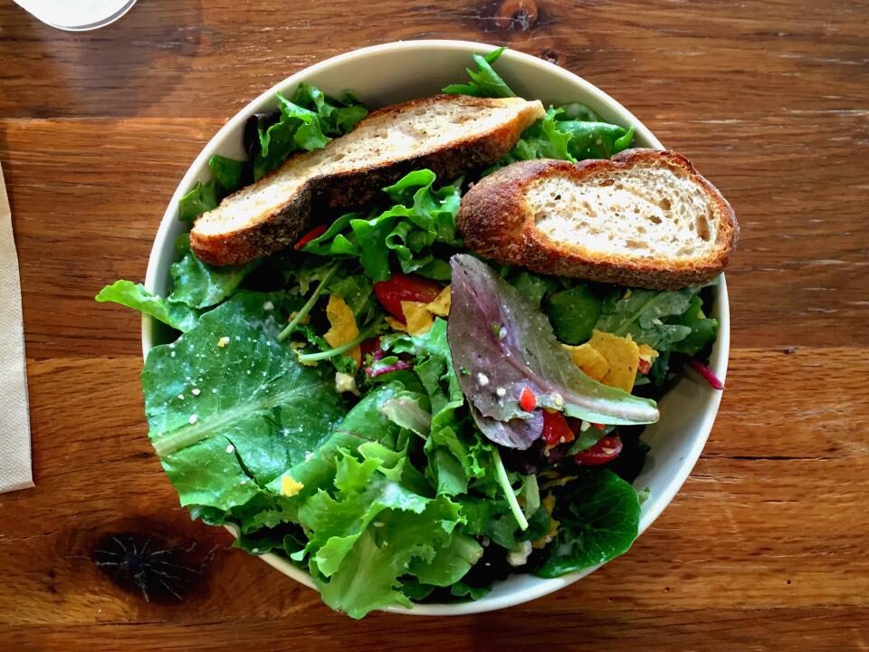 Ensalada fresca con pan tostado servida en un plato hondo